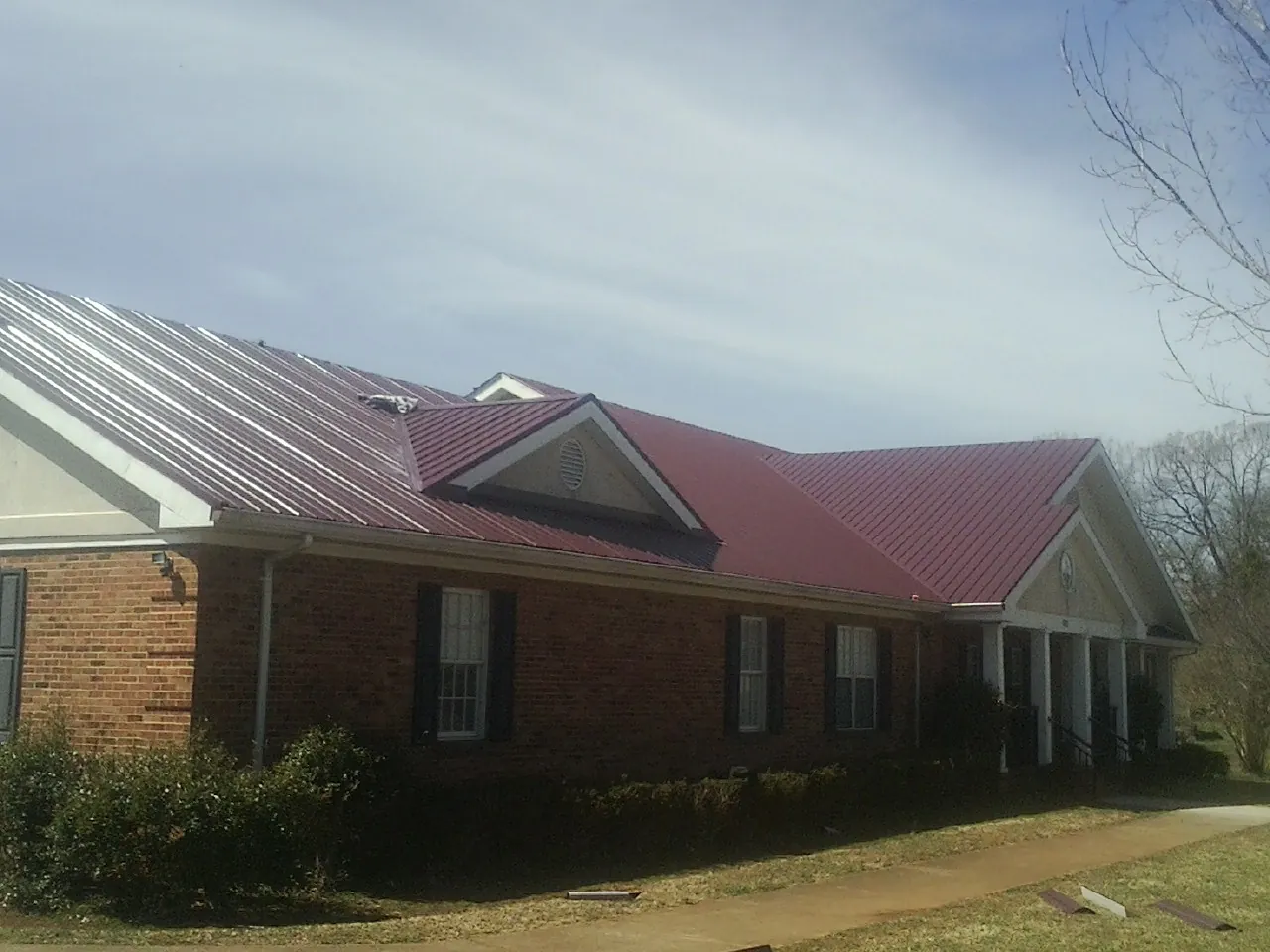 Red metal roof with gabled entries on a long brick building in Woodman