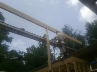 Carpenter setting a ridge beam over a new addition frame — Ice Dam Removal by Roofing Brothers in Woodman