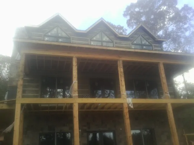 Dormers and porch framing on a large log home under construction — Roof Coating work by our crew in Woodman