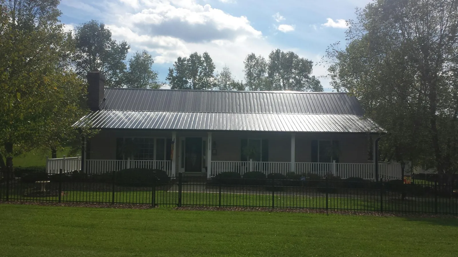 Gray metal roof on a brick ranch with a full width front porch — Gutter Guard Installation work by our crew in Woodman