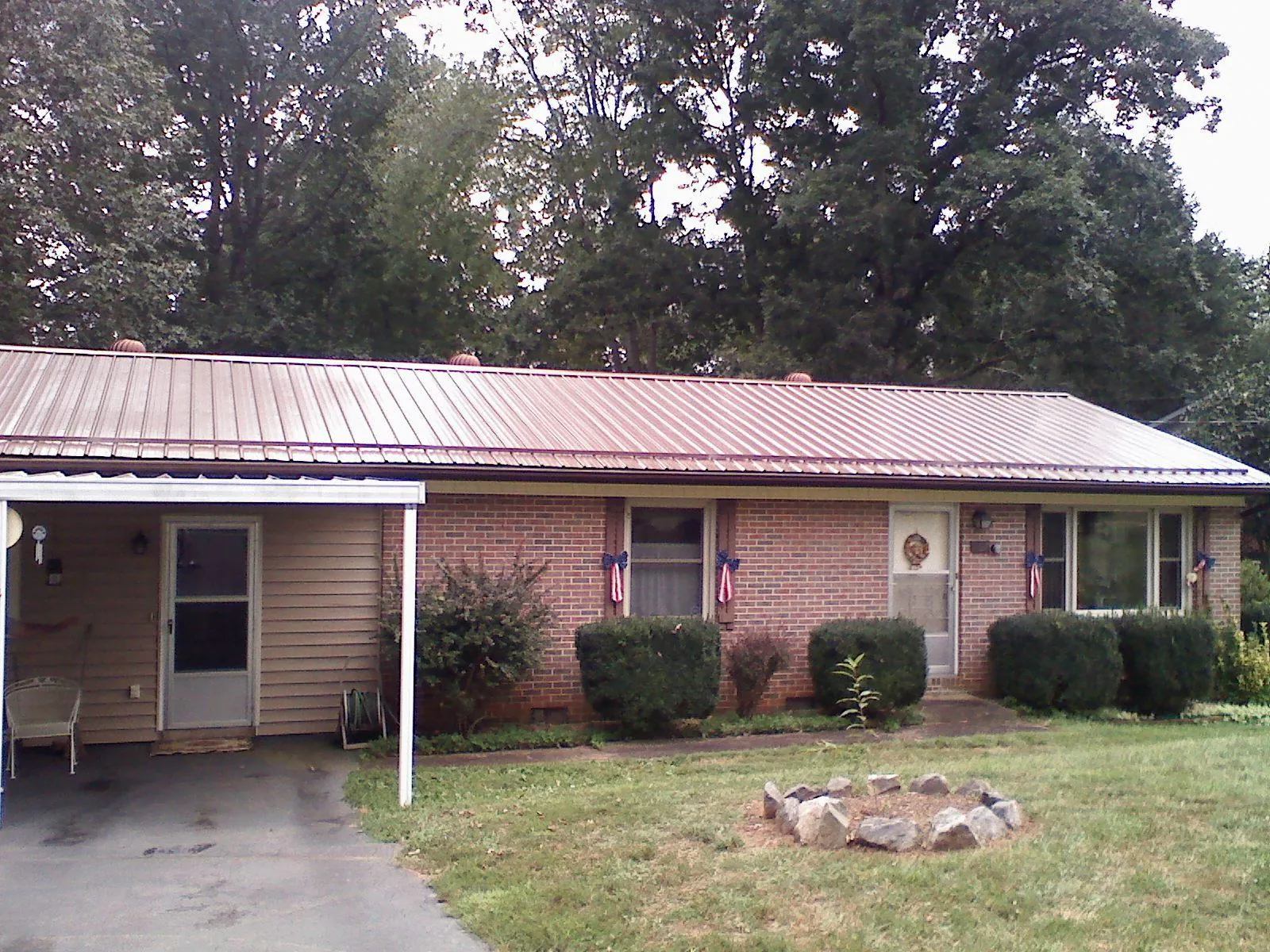 Bronze metal roof and carport on a brick ranch home — Roof Repair work by our crew in Woodman