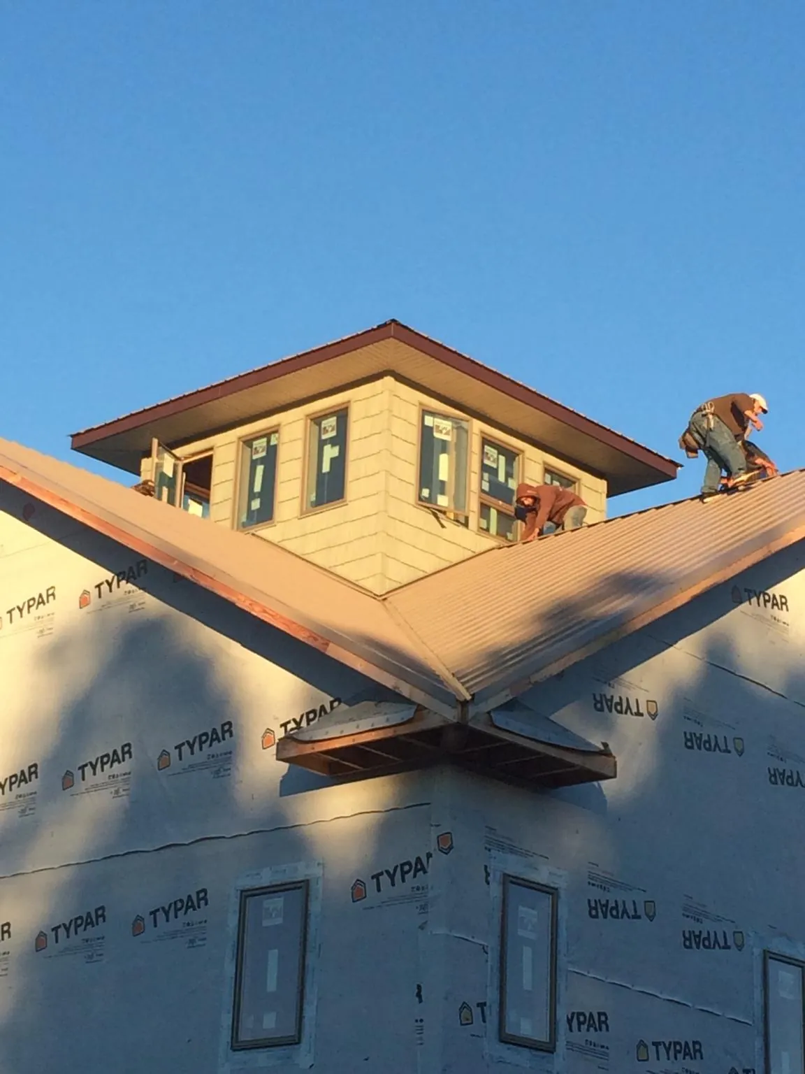 Roofers working around a rooftop cupola on a new metal roof at sunset — Roof Waterproofing in Woodman by Roofing Brothers